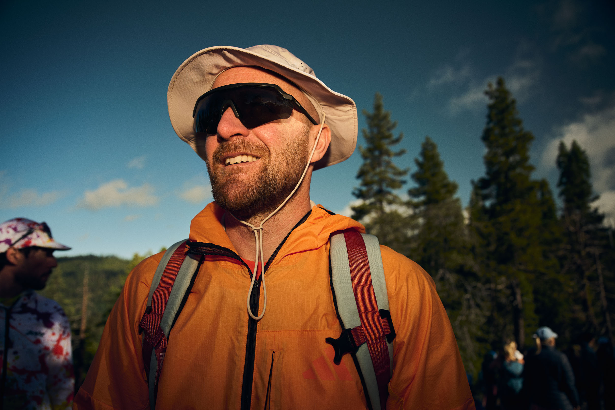 Portrait of an Adidas TERREX crew member in orange kit beneath a blue sky.