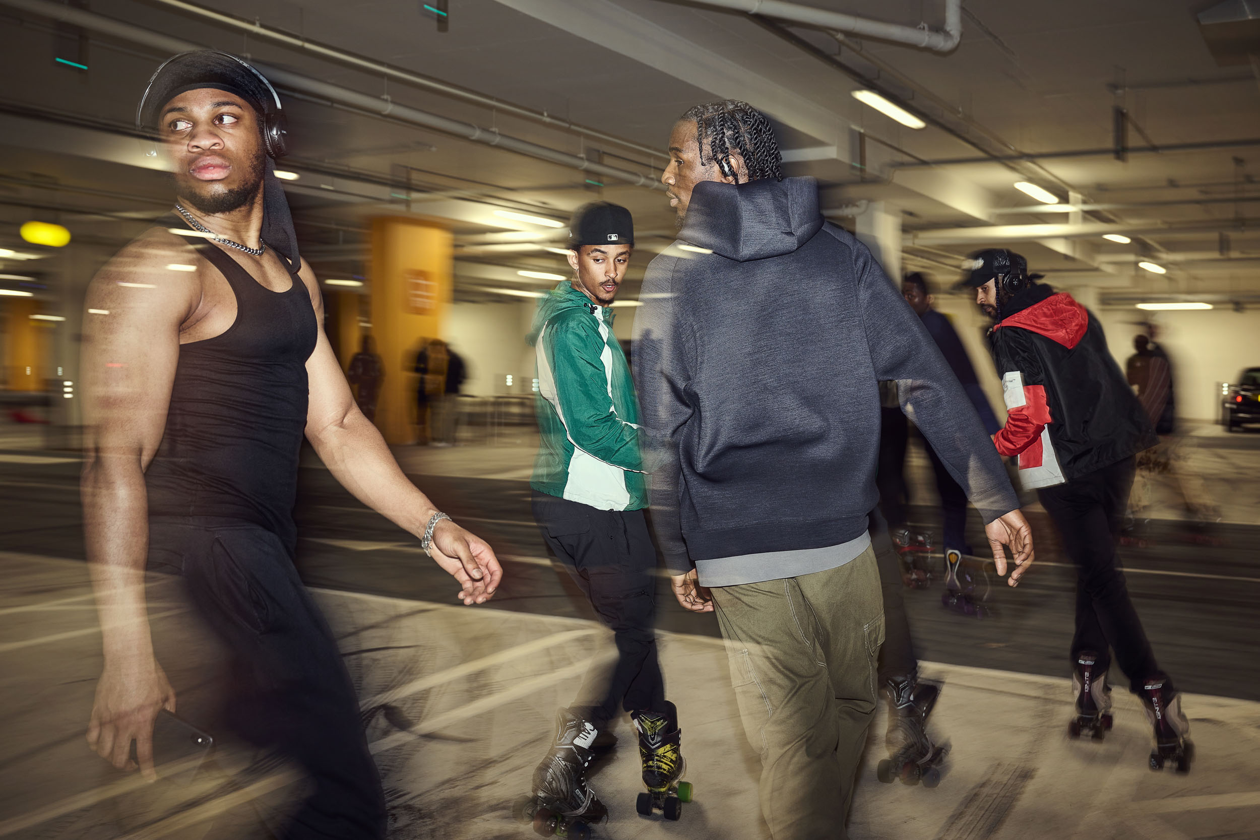 Three skaters roll together, one in headphones leading the group across the floor.