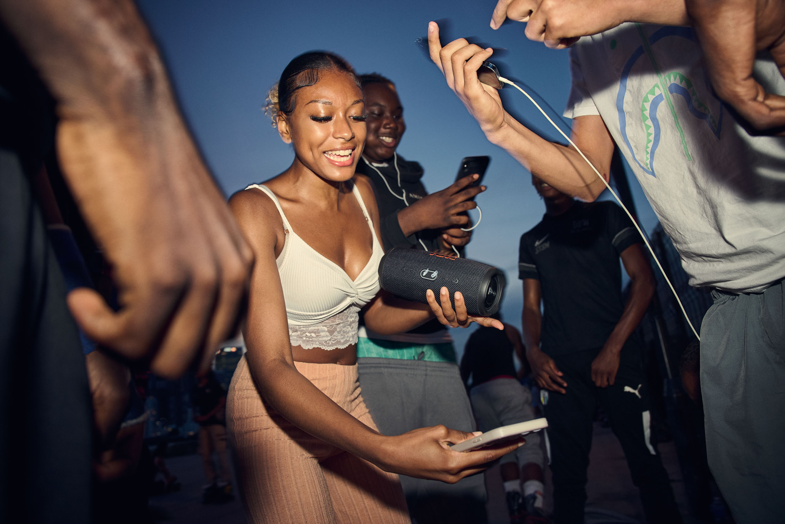 A skater laughs with a speaker in her hand as the music gets sorted out.