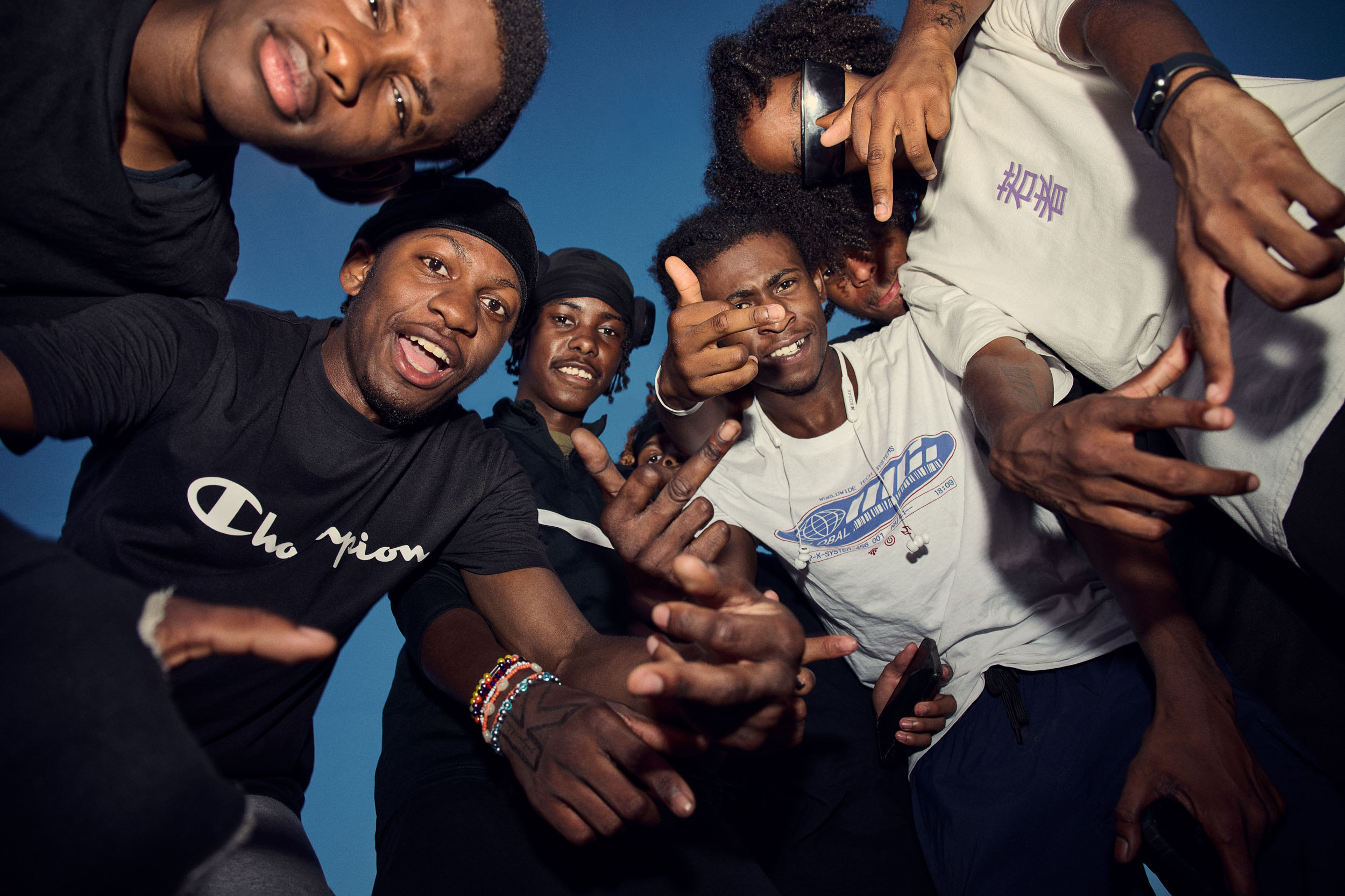 A group of skaters lean into the lens together against a deep blue evening sky.