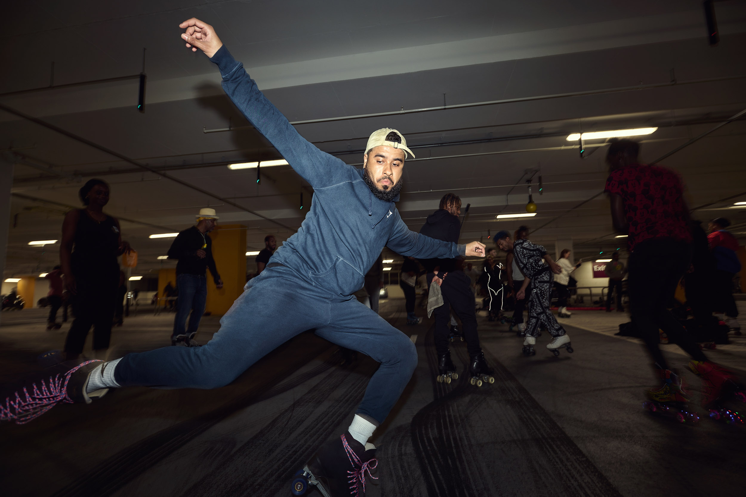 A skater stretches into a wide split legged move on the car park floor.