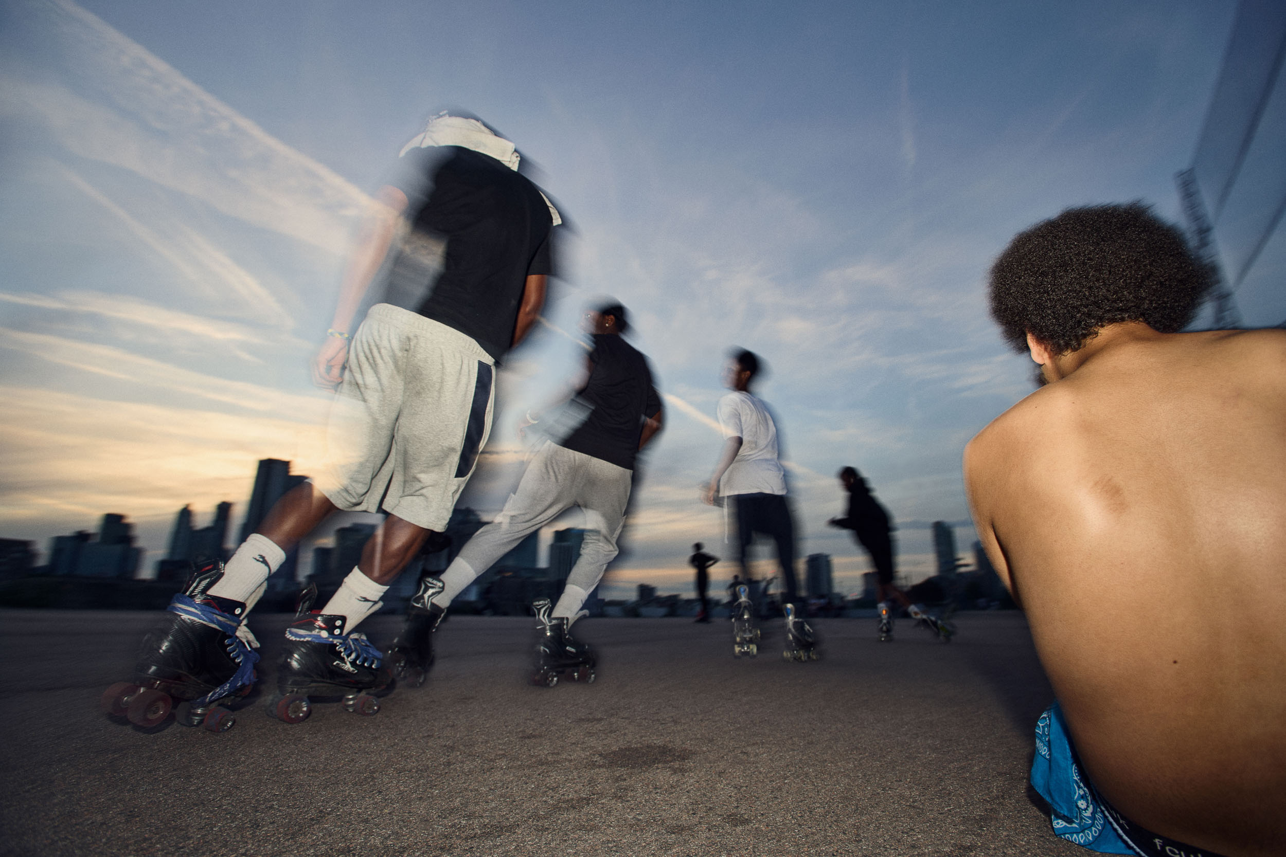 Skaters sweep past in a blur at sunset while one rests in the foreground.