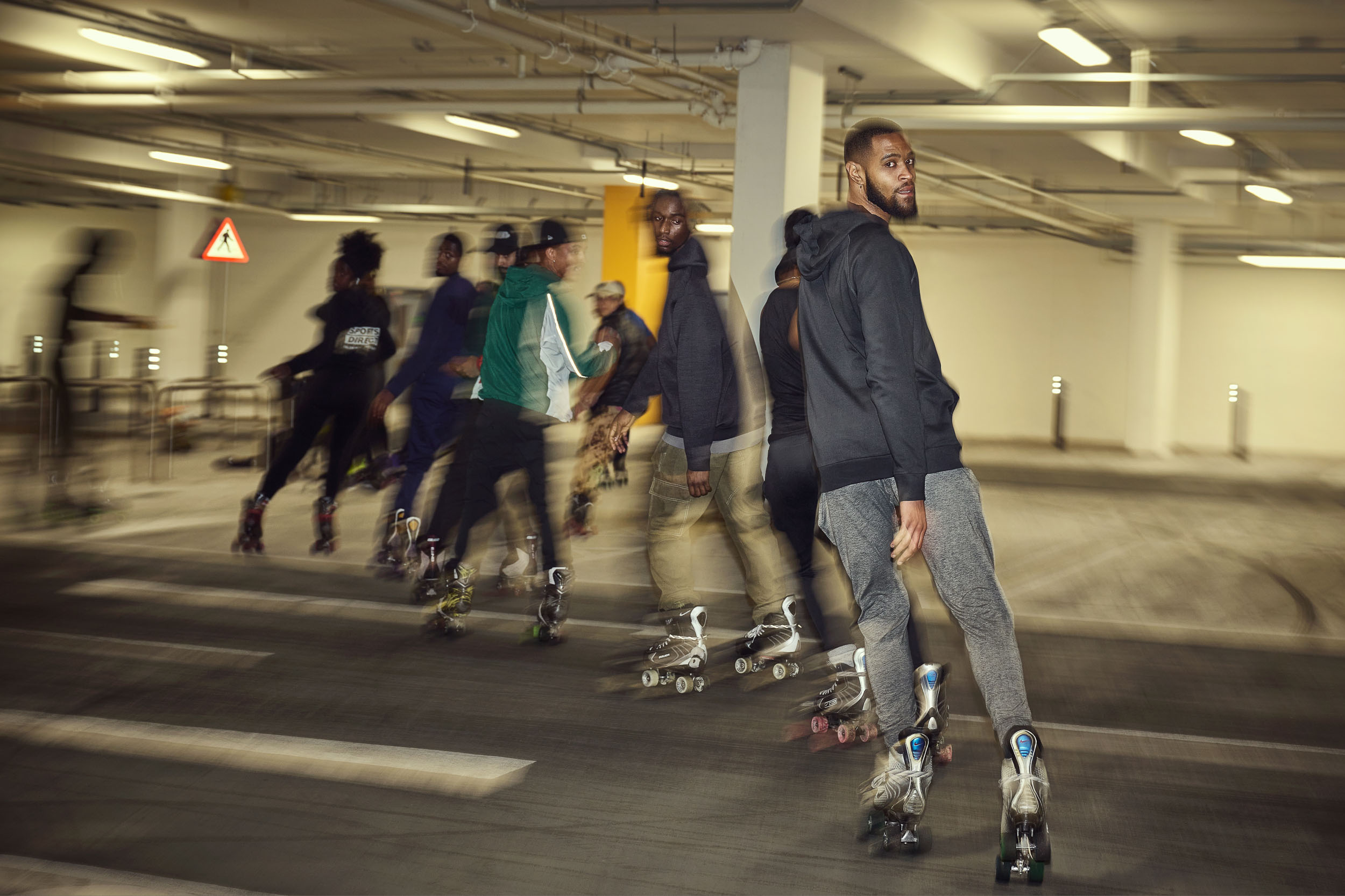 A line of skaters files past in the dark, one of them looking back at the camera.
