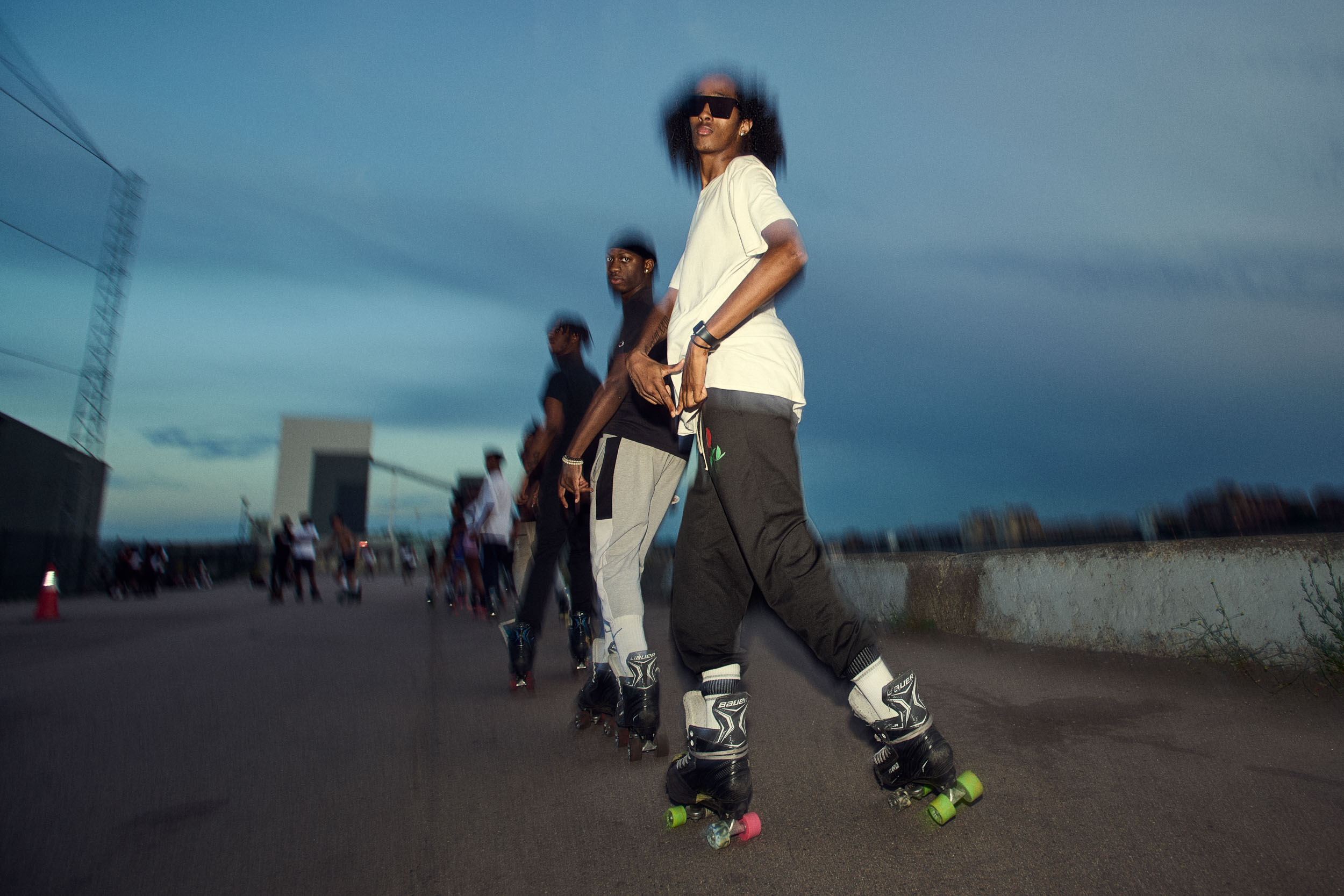 Skaters move in single file, each with a hand on the waist of the one in front.