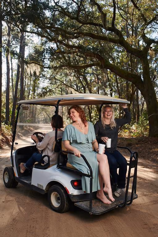 Visitors riding a golf cart beneath live oak trees on Daufuskie Island