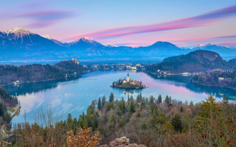 Panorama des Bleder Sees in Slowenien mit der Inselkirche und den umliegenden Julischen Alpen bei Sonnenuntergang