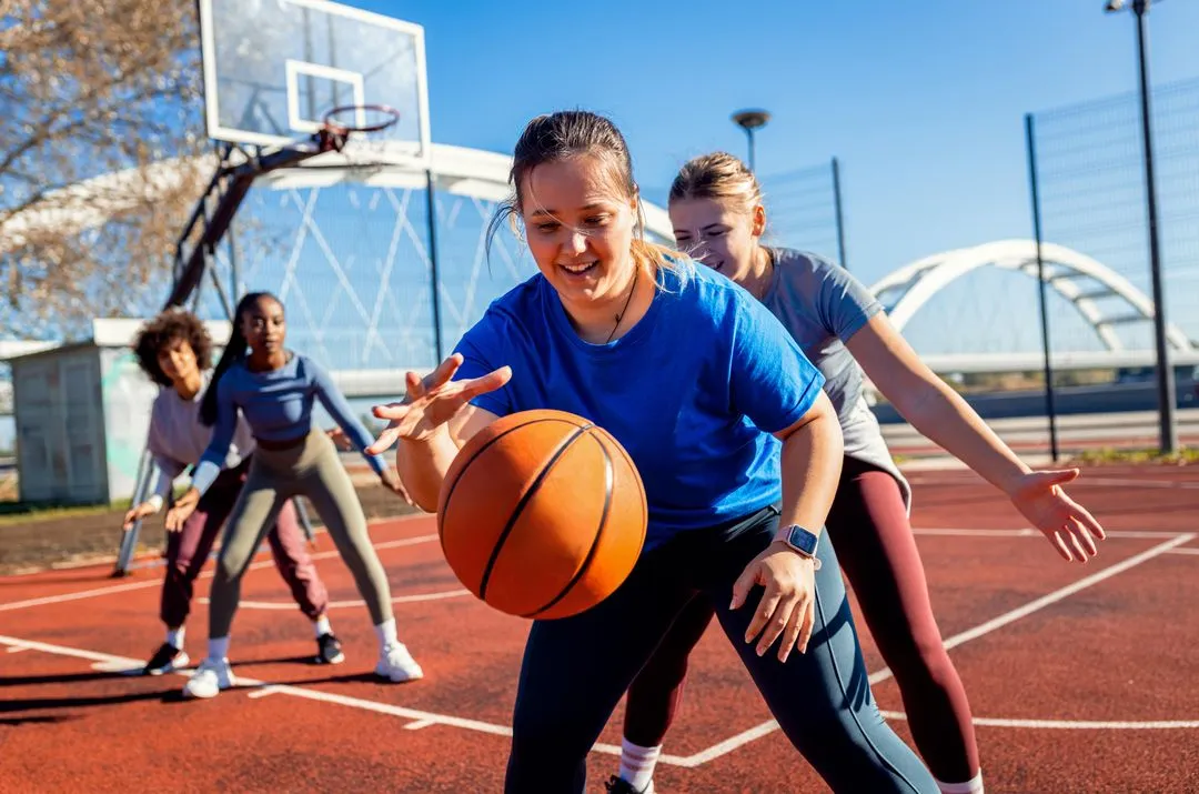 Piger der spille basket – illustration til førstehjælpskurser for personale der arbejder med sport, motion og foreninger.