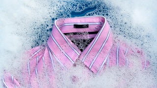 Channel in an ad break — a detergent commercial showing a pink striped shirt in soap suds