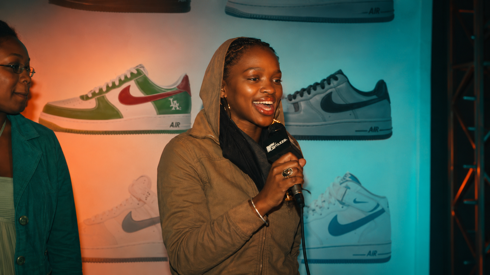 MTV VJ Fix, aka Fikile Moeti, takes the mic inside the Nike X MTV Air Force 1 25th anniversary experience, framed by a wall of iconic Air Force 1 silhouettes and the culture that defined the night. ©Jandré Louw