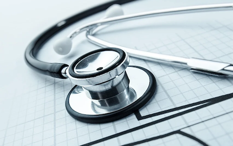 Close-up of a stethoscope resting on a medical chart with heart rate lines.