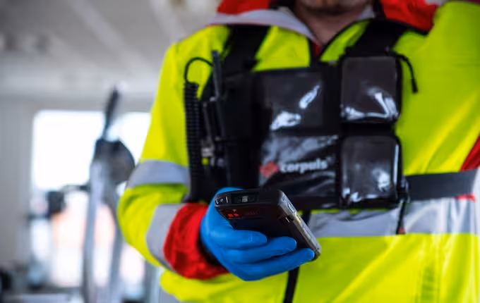 Rettungssanitäter in Warnschutzjacke hält corpuls-Gerät in der Hand