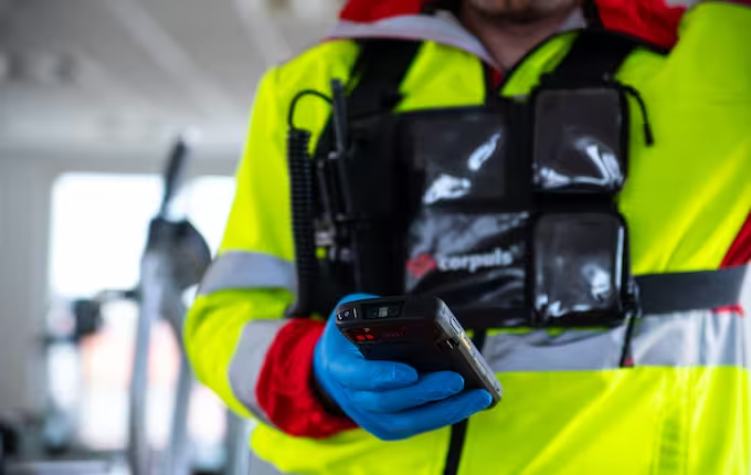Rettungssanitäter in Warnschutzjacke hält corpuls-Gerät in der Hand
