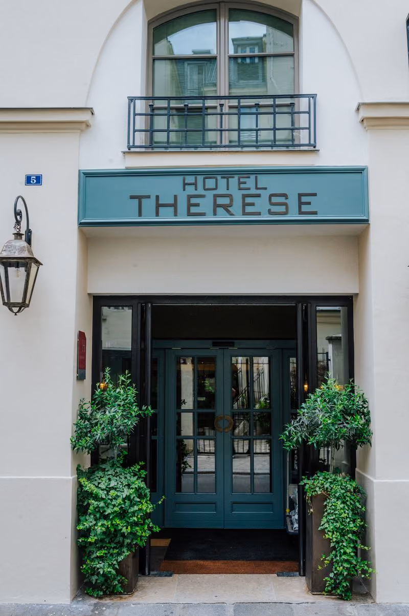 Front of theHotel Therese ; the hotel's entrance doors with the two plants in front