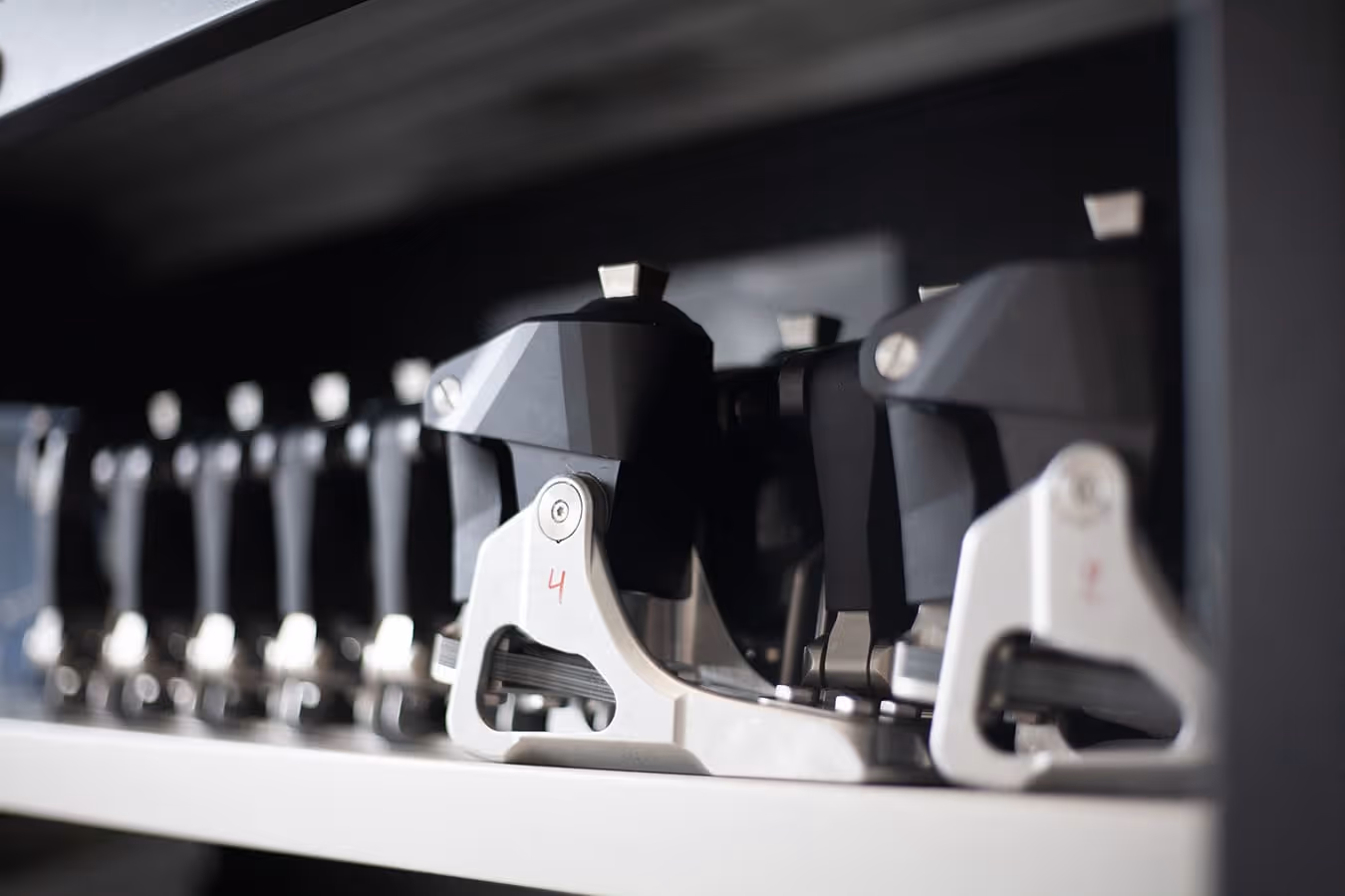 Close-up of a row of black and silver ski bindings on a shelf.