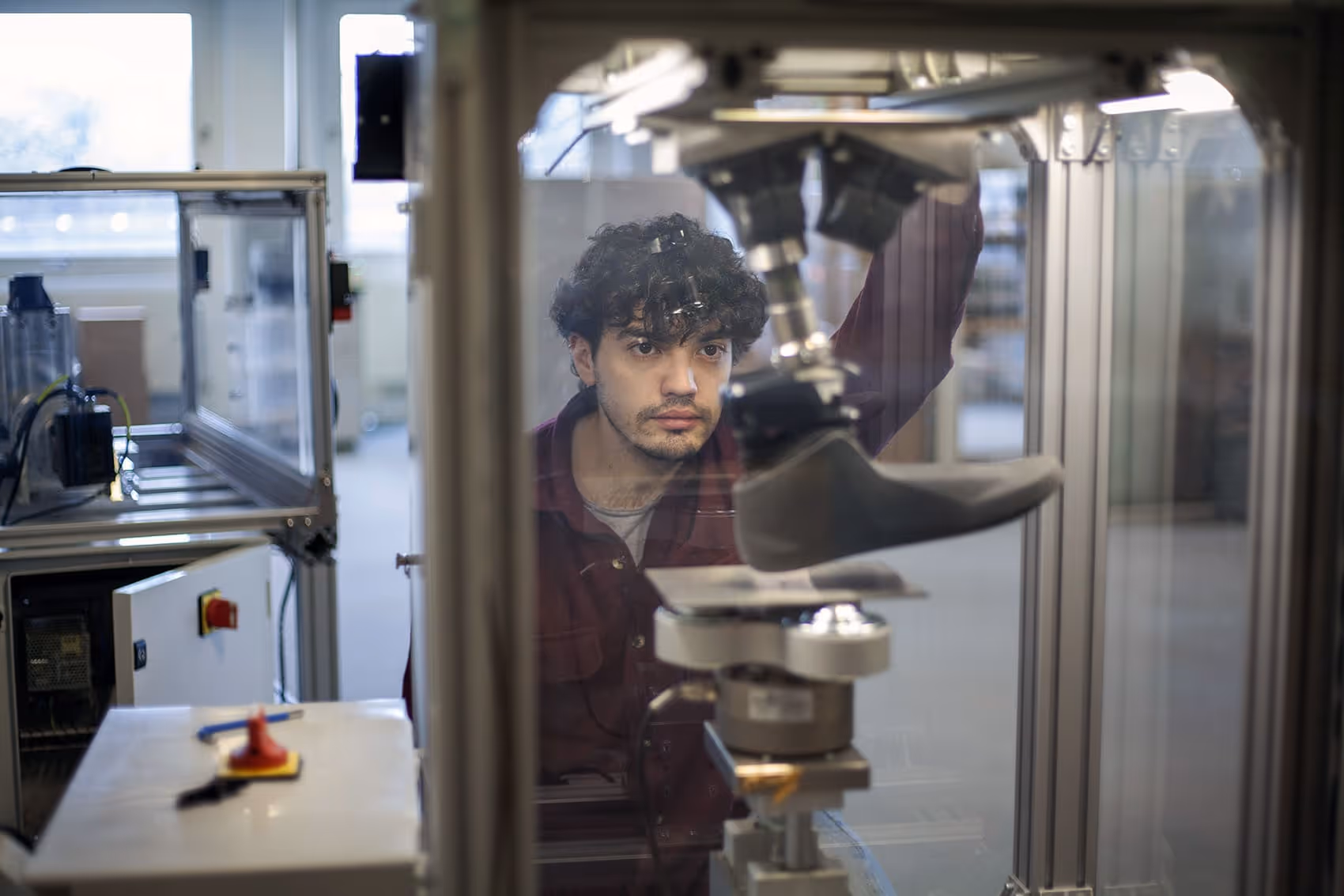 Engineer inspecting a prosthetic leg prototype inside a laboratory testing machine.