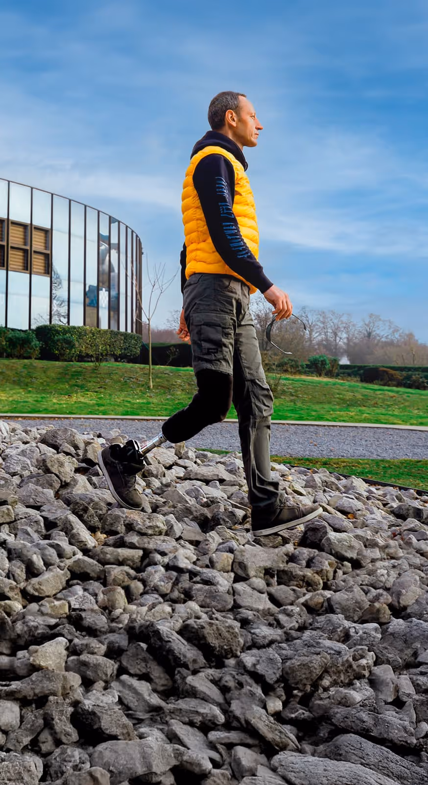 User walking on an unven terrain with stones and gravel with a prosthetic leg outdoors