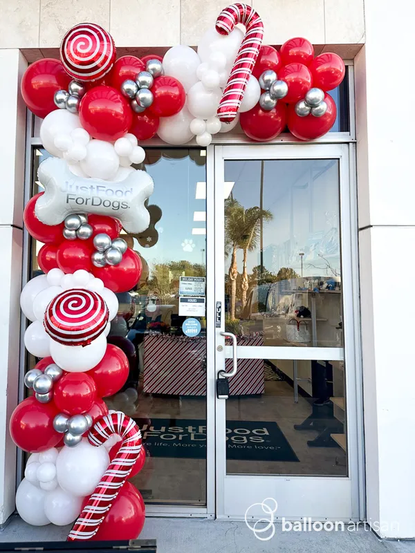 A balloon candy cane winter balloon garland with company logos on a building entryway.