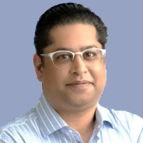 Portrait of a man with glasses wearing a light blue striped shirt against a solid blue background.