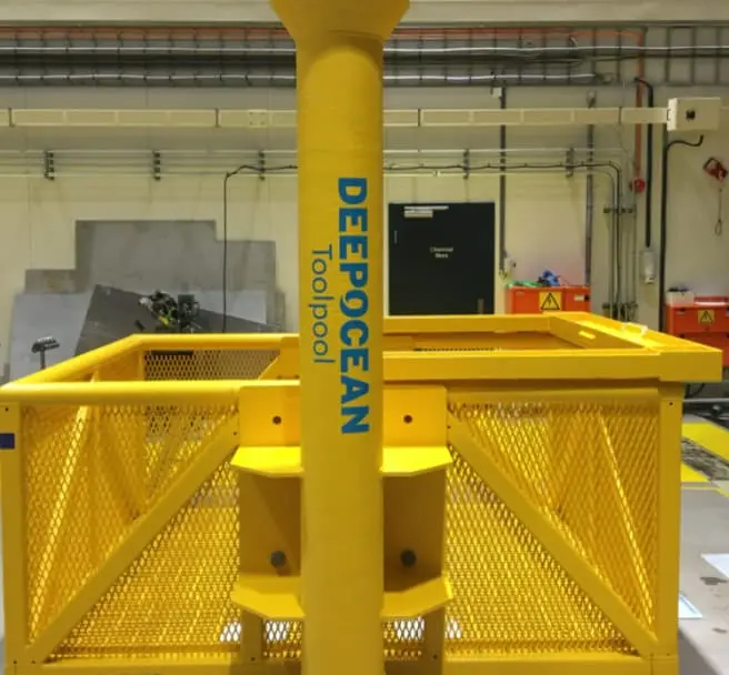 Yellow metal offshore structure labeled DEEPOCEAN Toolpool in an industrial warehouse setting.