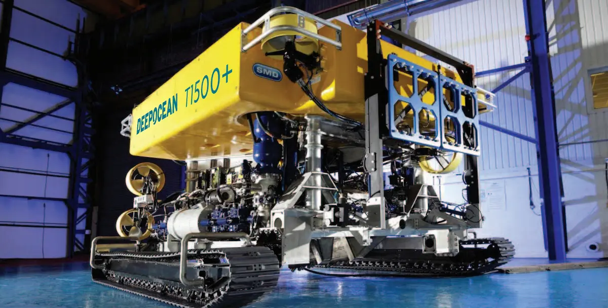 Yellow DeepOcean T1500+ underwater remotely operated vehicle on metal tracks indoors.