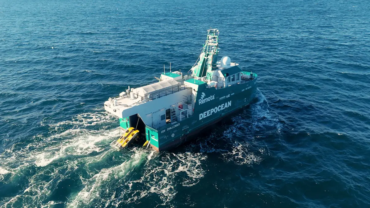 Remotely operated USV Challenger vessel on open water with DEEPOCEAN branding, deploying equipment.