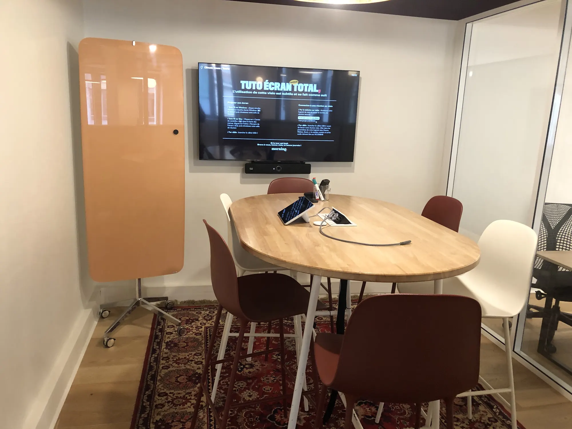 Salle de réunion équipée d'un écran et d'une barre de visioconférence
