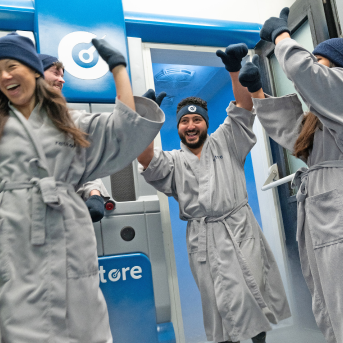 Woman wearing a robe entering a cryotherapy machine while mist pours out around her