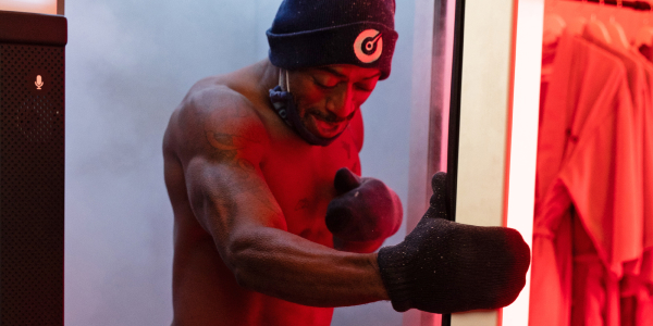 Man exits Cryotherapy chamber next to smiling woman to help manage his cortisol at Restore Hyper Wellness.