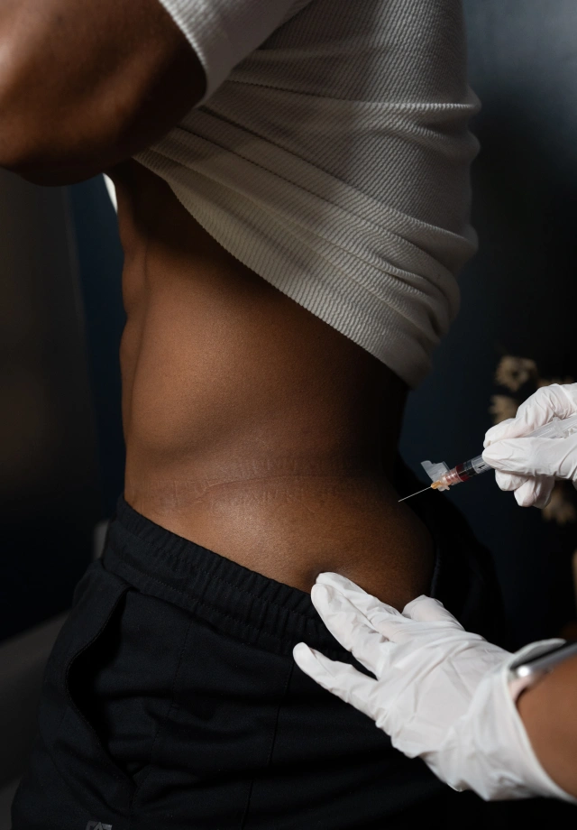 A man receiving an intramuscular shot from a Restore nurse wearing white gloves