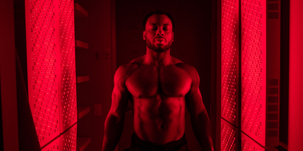 Woman stands between two Red Light Therapy panels at Restore Hyper Wellness