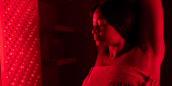 Woman smiling, using Red Light Therapy for pain management at Restore Hyper Wellness