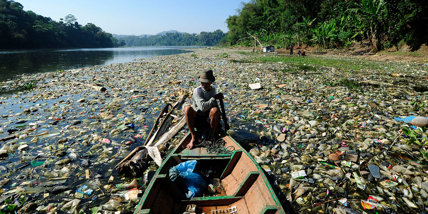 Photo d'une pirogue qui traverse un lac rempli de déchets.