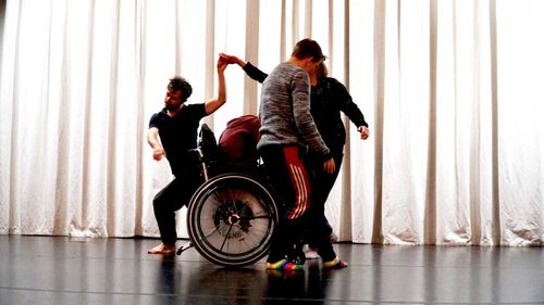 Fyra människor dansar tätt, tätt framför en vit kuliss. Man ser nästan inte var en person börjar och nästa slutar.