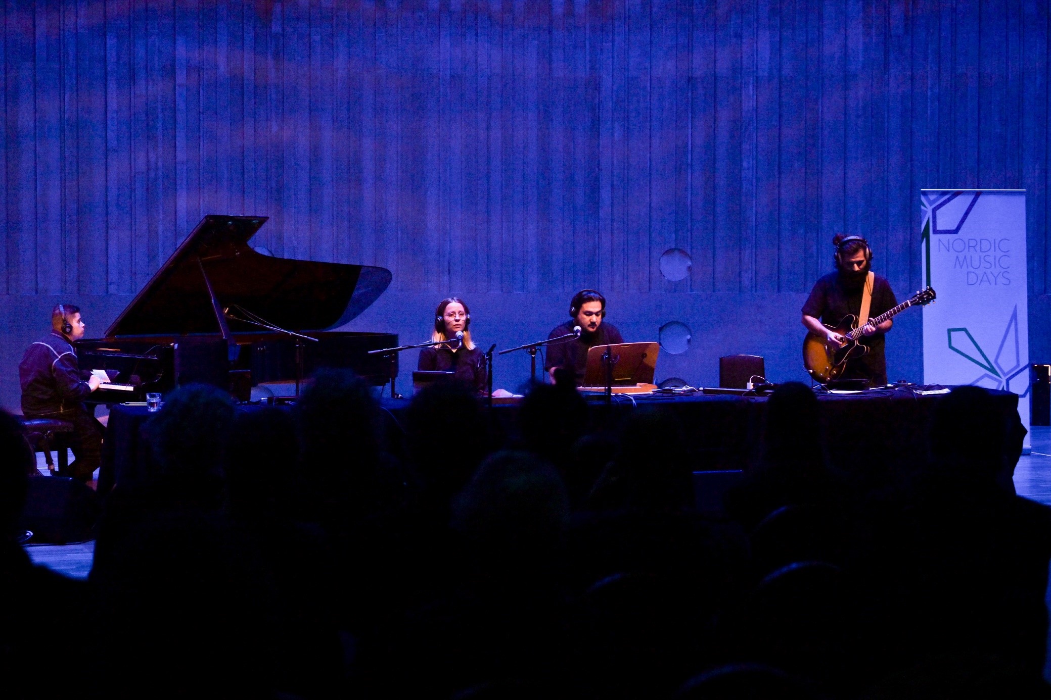 Fyra musiker uppträder på scen under Nordic Music Days, upplysta i blått.