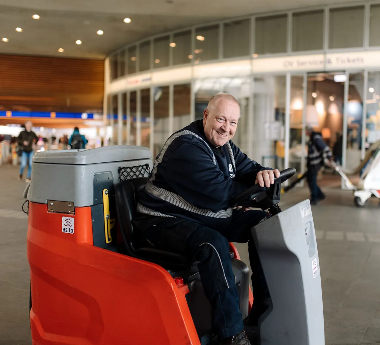 Een Asito-medewerker maakt met een schrobmachine vloeren schoon