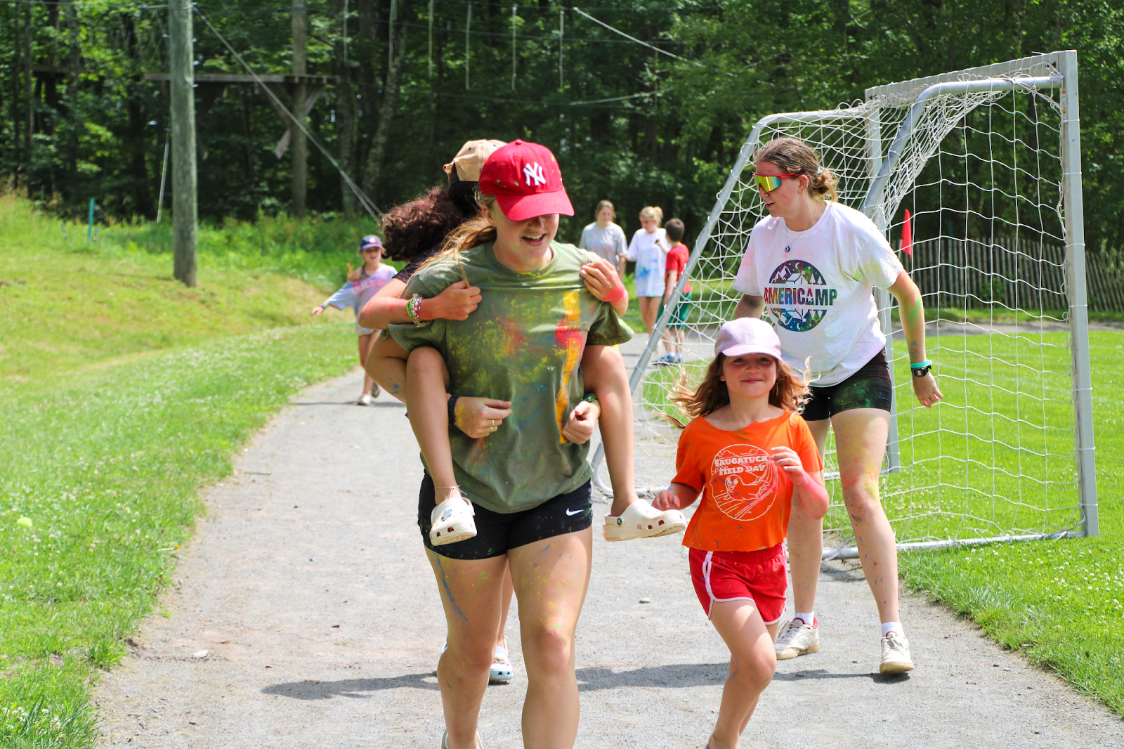 Campers and AmeriCamp camp counsellors running around a sports field outdoors