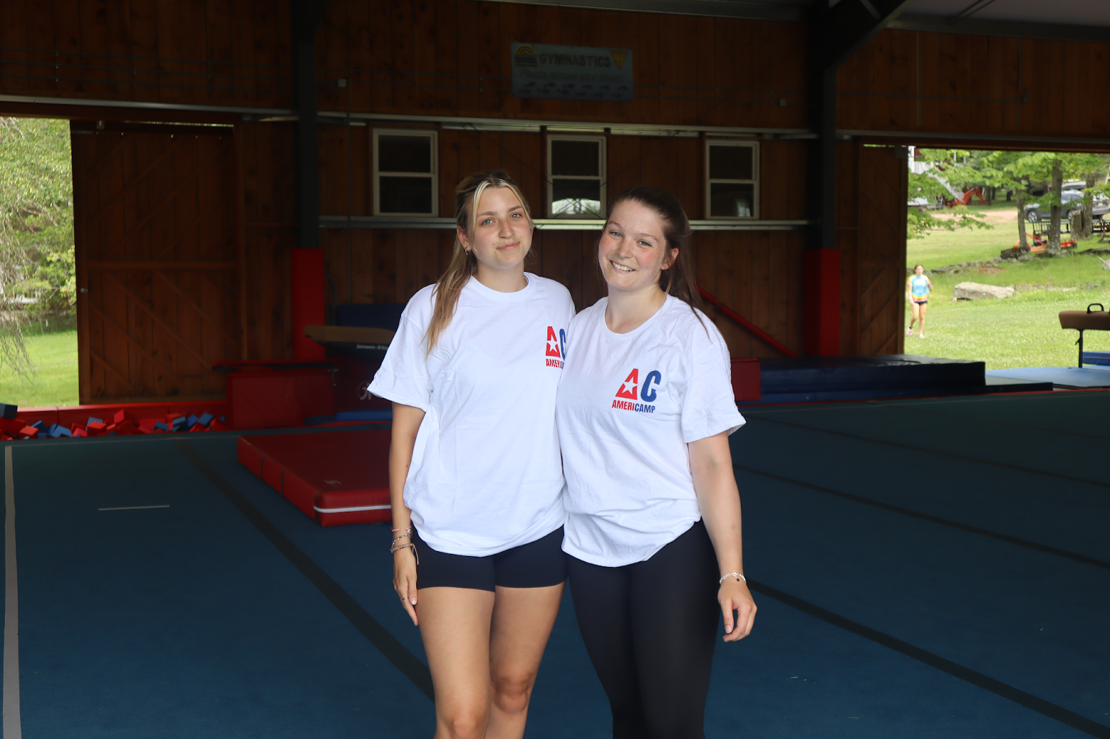 Two AmeriCamp camp counsellors posing for a photo in a gymnastics hall