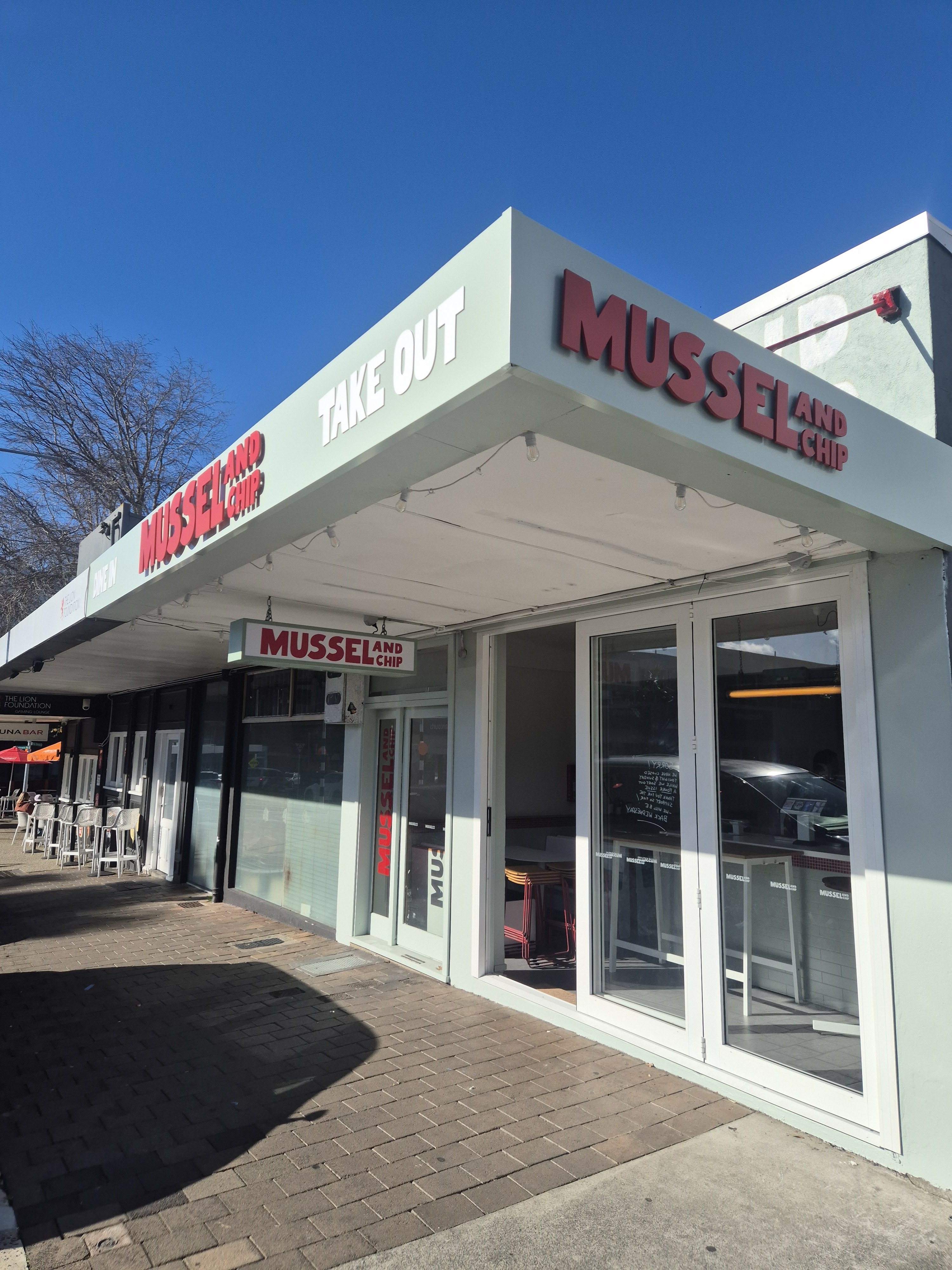 Mussel and Chip shopfront with takeaway signage and outdoor seating.