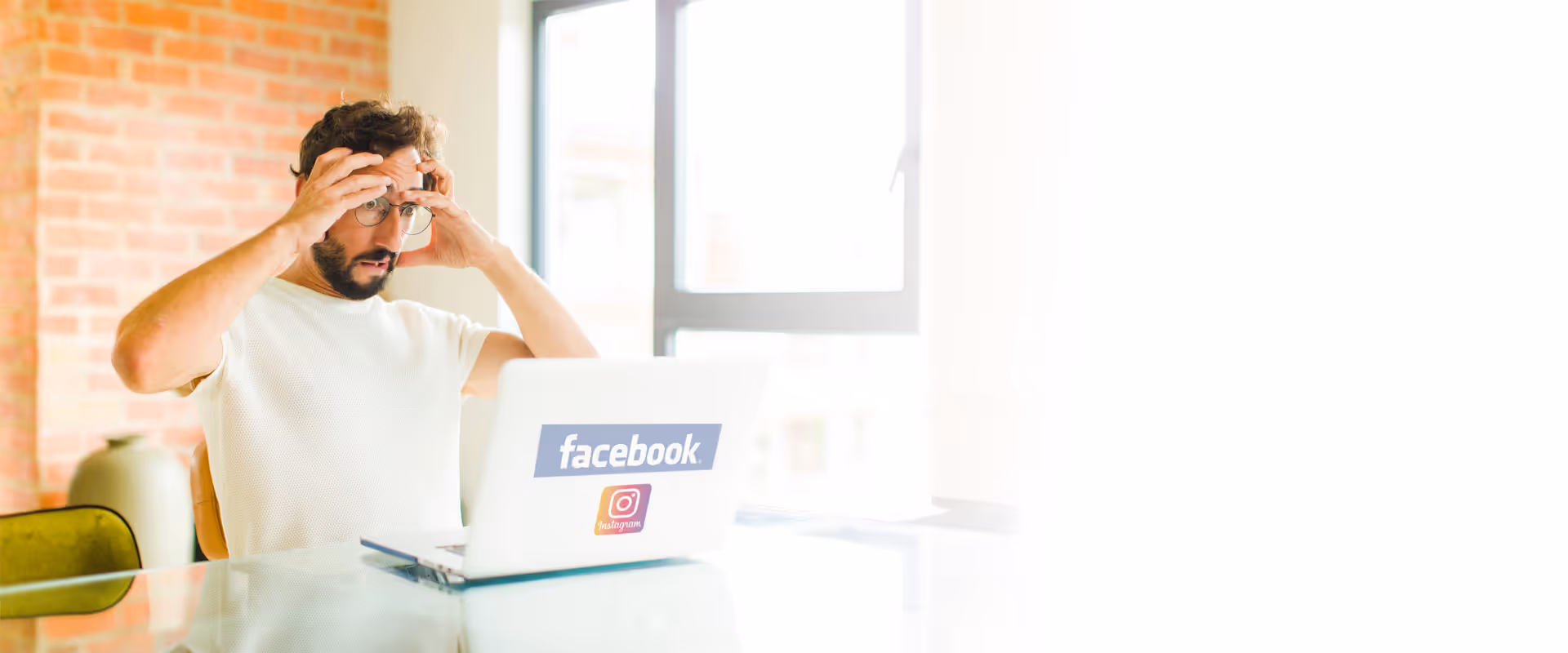 Ein Mann sitzt schockiert an seinem Laptop mit den Logos von Instagram und Facebook.