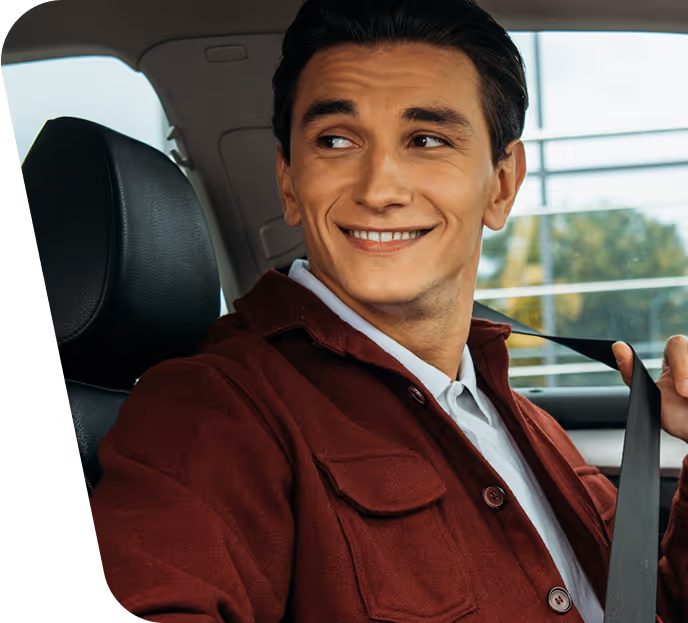 Ein Mann sitzt in seinem Auto und blickt freundlich nach links.