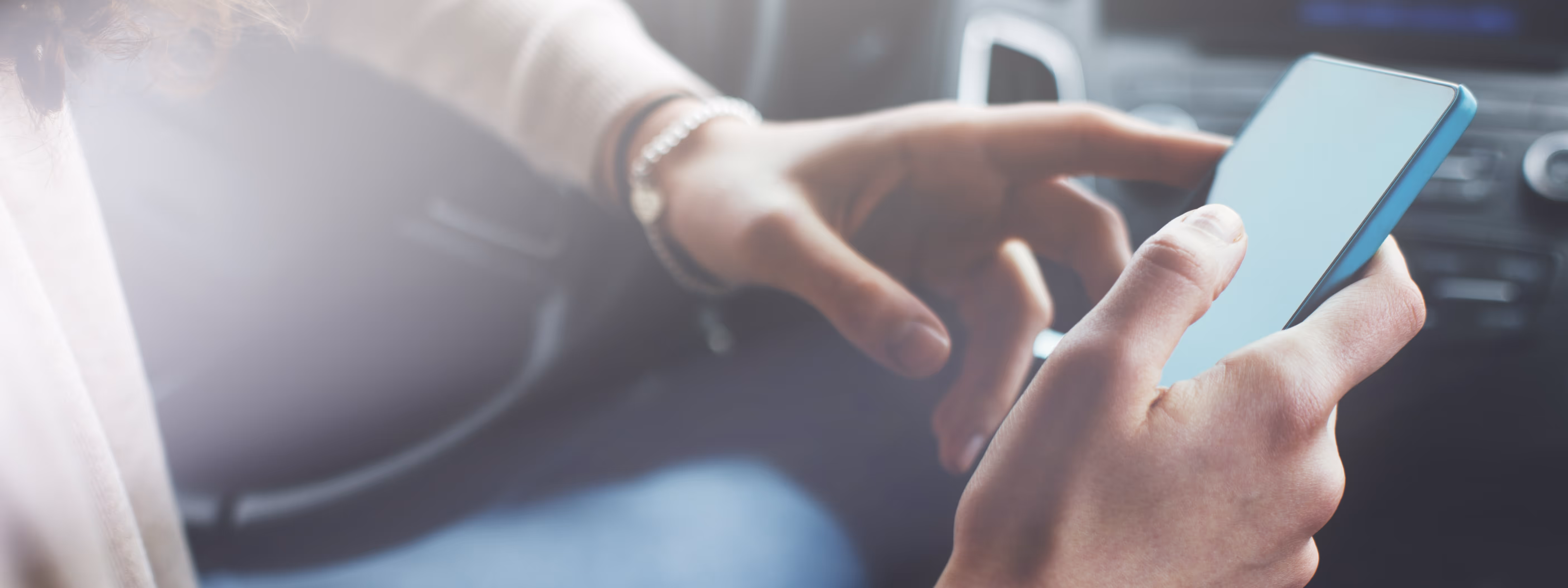 Eine Person hält ein Handy in der Hand, während sie im Auto sitzt.