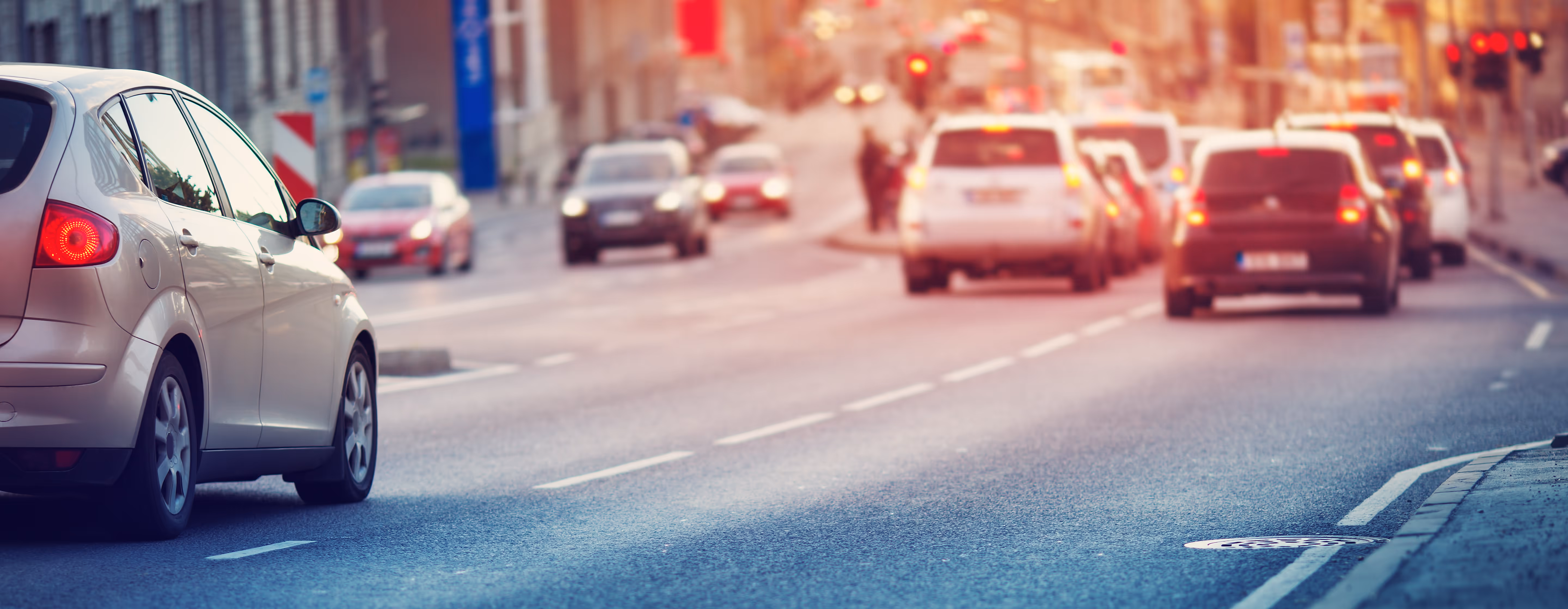 Alltäglicher Straßenverkehr, eine rote Ampel im Hintergrund.