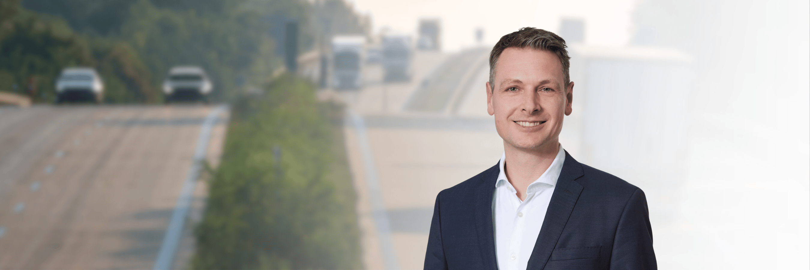 Anwalt Timo Schell. Im Hintergrund leicht verschwommen eine Autobahn in Deutschland.