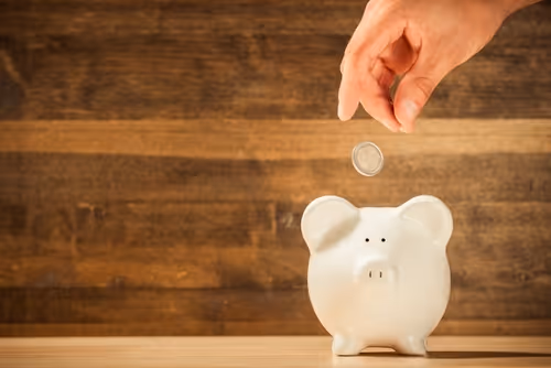 Ein Sparschwein, in das Geld eingeworfen wird