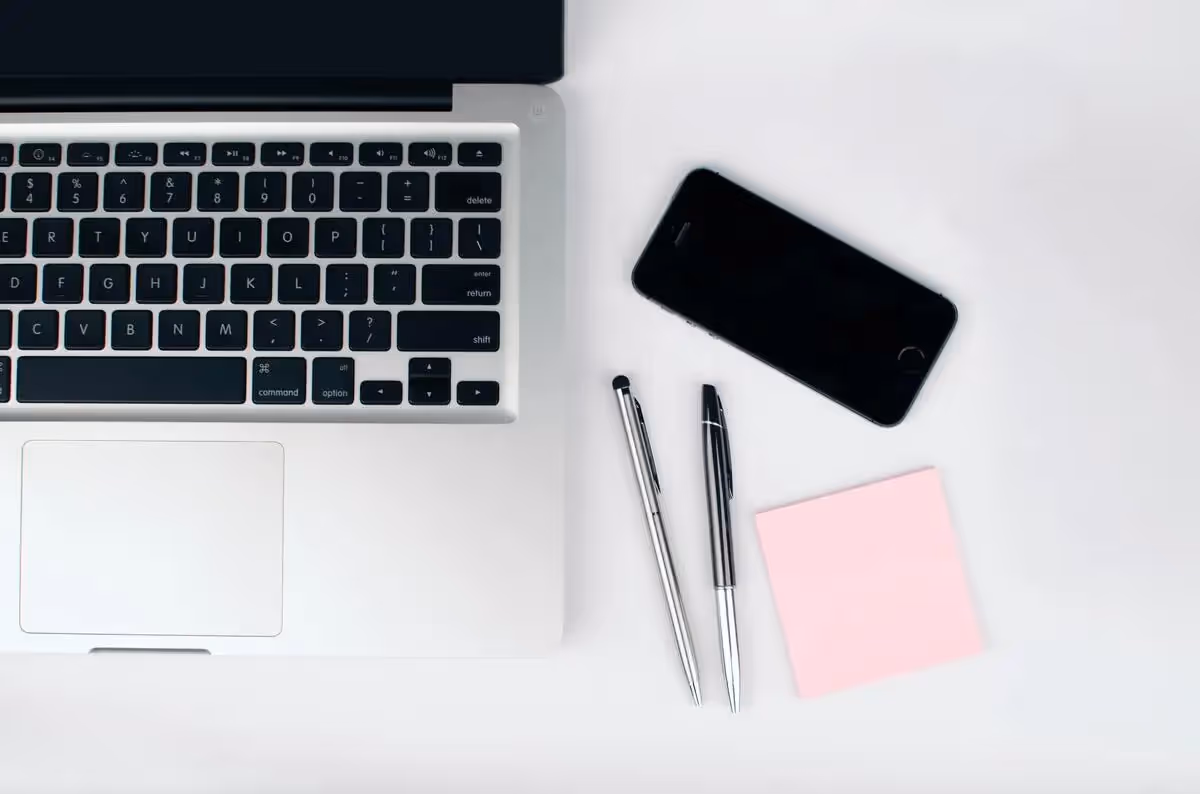 Laptop mit Handy und Stiften auf heller Oberfläche