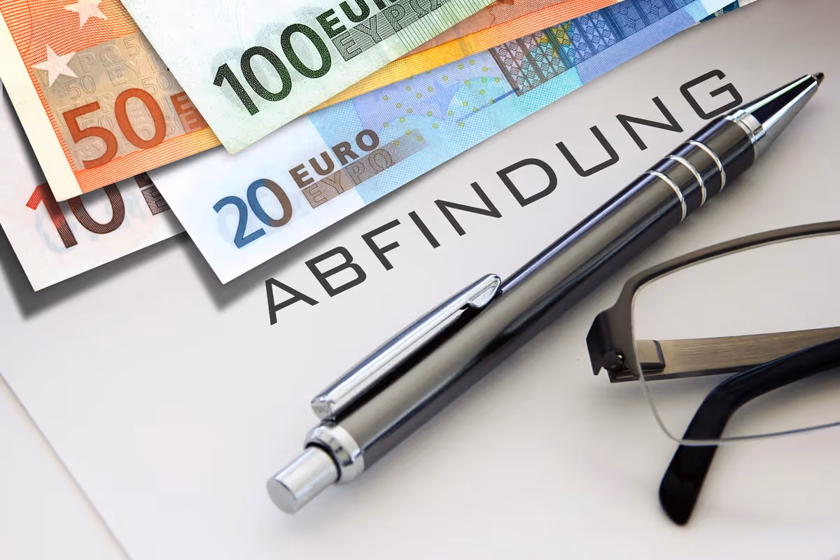 Abfindung auf Papier mit Geldscheinen und Stift