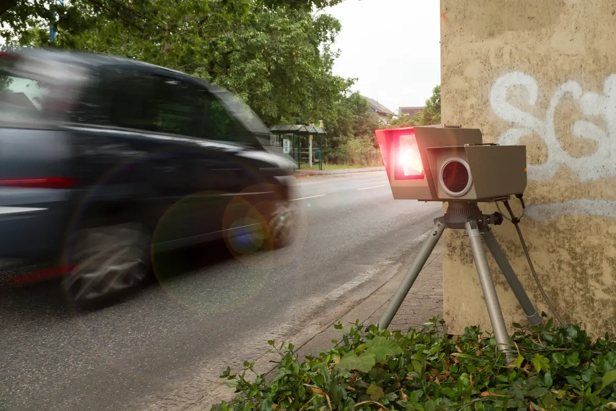 Ein obiler Blitzer wird ausgelöst, während ein Auto daran vorbeifährt