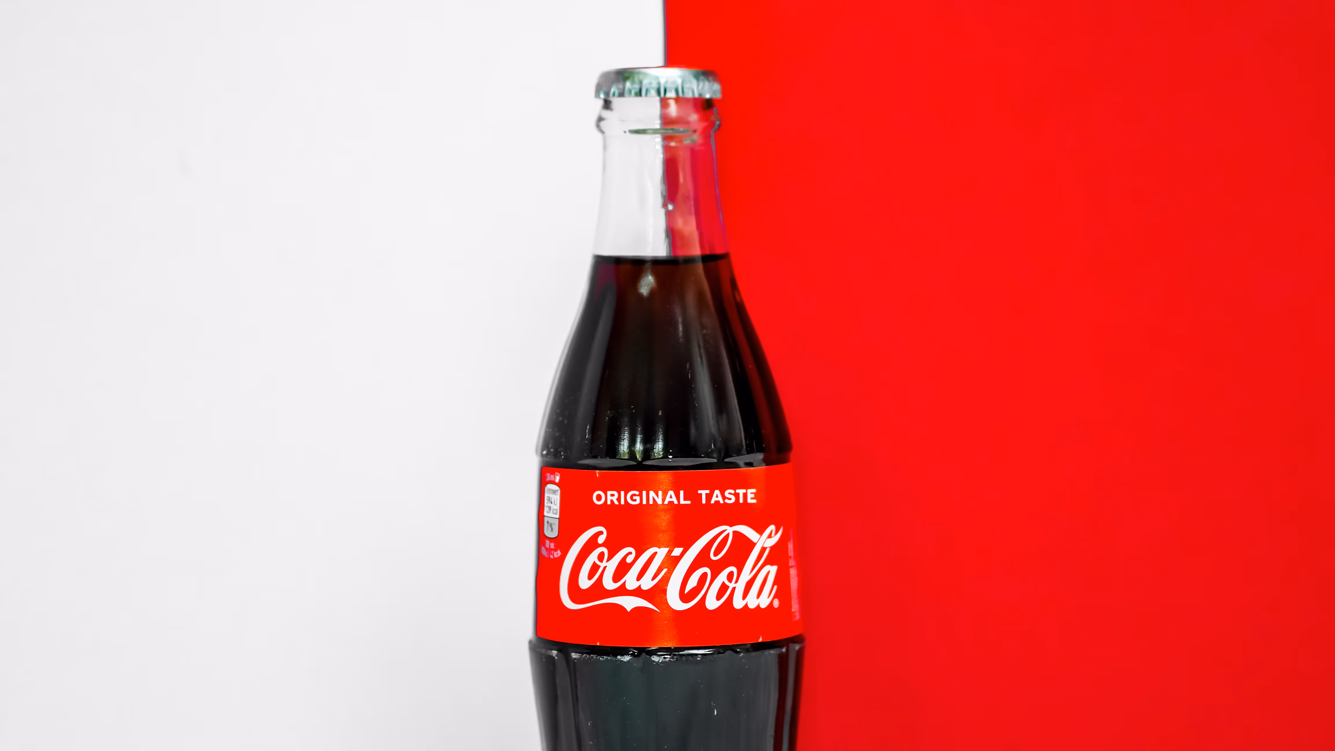 Coca-Cola bottle on half white, half red background.