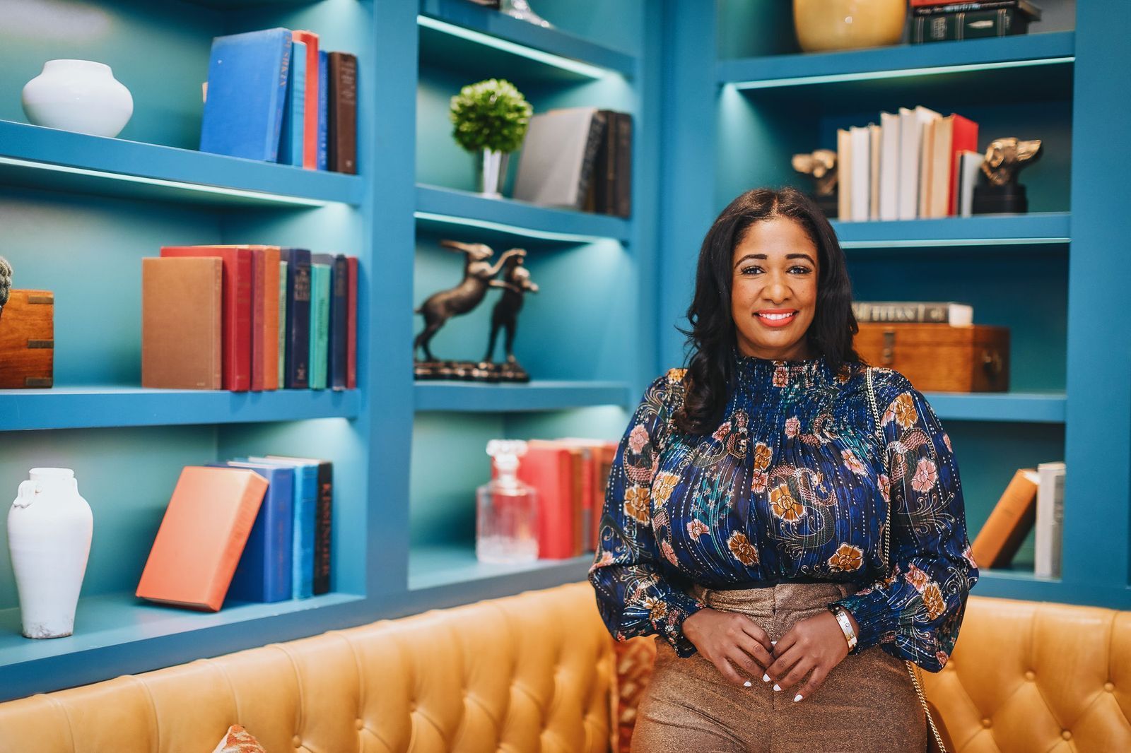 A Black woman posing in front of a bookshelf.