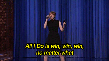 A woman with a microphone singing, "All I do is win, win, win, no matter what."